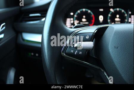 Defocused backlight of LED dashboard behind car steering wheel with heating and voice control buttons on it Stock Photo