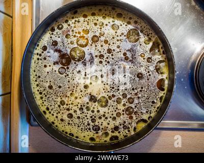 Top view of a round frying pan with grease eyes on an electric stove. Stock Photo