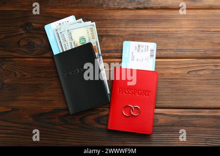 Honeymoon concept. Two golden rings, passports, money and tickets on wooden table, top view Stock Photo