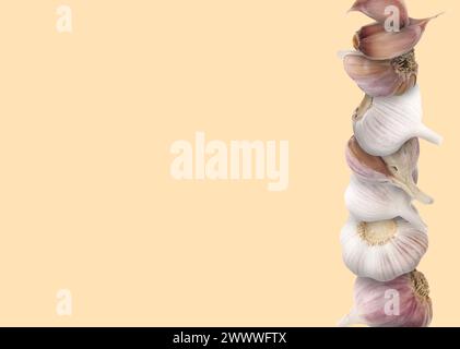Stacked heads and cloves of garlic on beige background, space for text Stock Photo