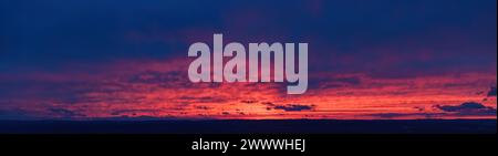 Fire on the sky: Aerial, long panoramic view of colorful, orange and red colored streakes of cirrus clouds on deep blue evening sky.  Ideal for sky re Stock Photo