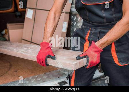 Closeup of Man unloading wooden package and boxes from a delivery van, emphasizing logistics, efficiency, and delivery services industry. Stock Photo