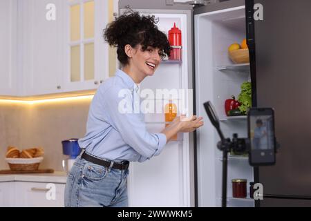 Smiling food blogger explaining something while recording video in kitchen Stock Photo