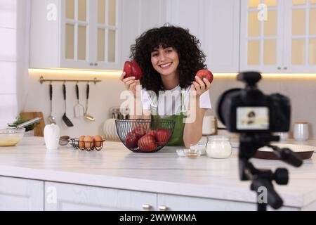 Smiling food blogger explaining something while recording video in kitchen Stock Photo