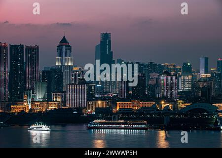 At night, by the Yangtze River, under the sunset, skyscrapers in Wuhan are illuminated, and ships are parked on the river surface Stock Photo