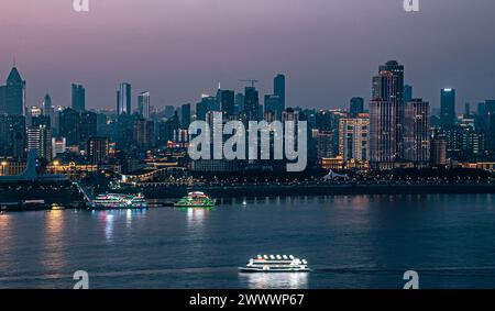 At night, by the Yangtze River, under the sunset, skyscrapers in Wuhan are illuminated, and ships are parked on the river surface Stock Photo