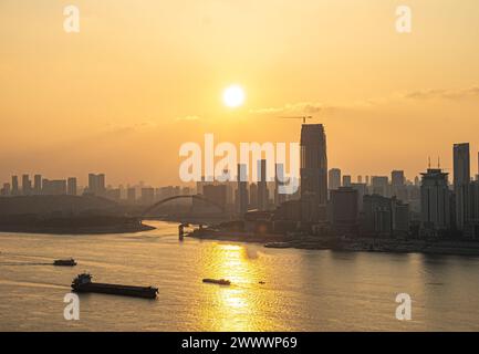 At sunset, bridges and buildings stand on both sides of the Yangtze River, with ships sailing on the river surface Stock Photo