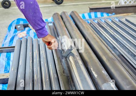 Worker using paint roller and painting on metal  in factory Stock Photo