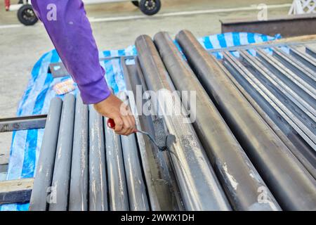 Worker using paint roller and painting on metal  in factory Stock Photo