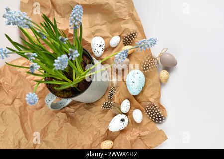 Easter eggs and light blue muscari flowers in cup on a white table. Easter still life. Top view Stock Photo