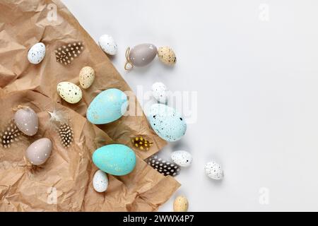 Easter eggs and feathers on a brown kraft paper background on a white table. Top view. For easter greeting cards with copy space. Stock Photo