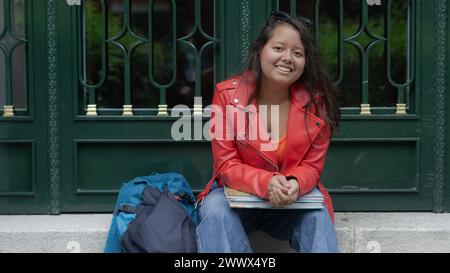 young student sitting on the staircase smiling Stock Photo