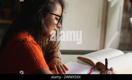 young woman seated studying at a glass table Stock Photo