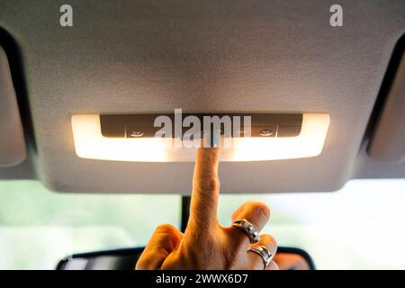 Woman's hand turning on a car interior light. Stock Photo