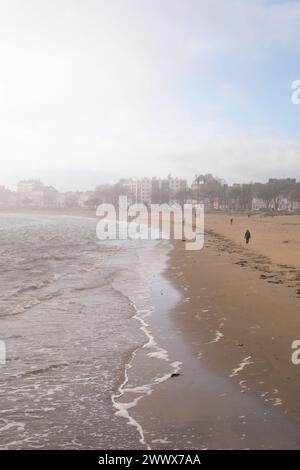The people walking on a sandy beach. Saint Nazaire Stock Photo
