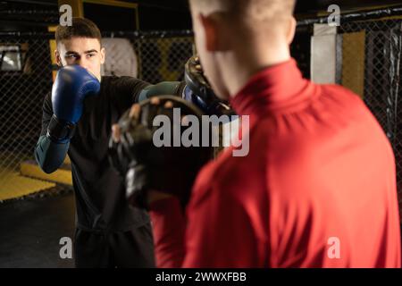 Boxing athlete punch to his opponent in sparring. Two male boxers fighting in a boxing ring. Stock Photo