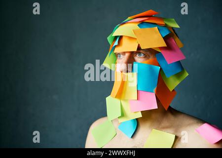 Close up portrait of man covered with colorful sticky notes all over his face and body over gray background with copy space Stock Photo