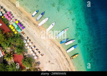 Top down view of colorful sunshades and tourist boats on a tropical beach Stock Photo