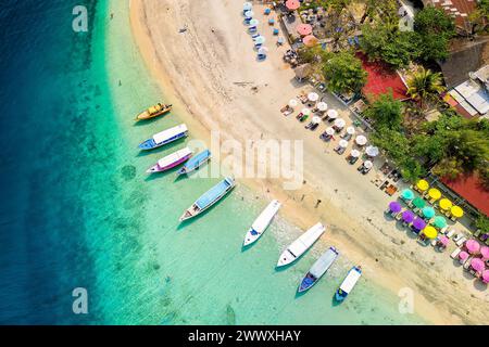 Top down view of colorful sunshades and tourist boats on a tropical beach Stock Photo