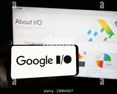 Person holding smartphone with logo of annual developer conference Google IO in front of website. Focus on phone display. Stock Photo