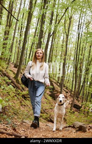 Cheerful woman walking her pet dog out while having backpacking trip with companion Stock Photo