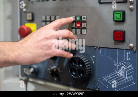 Worker pressing buttons on CNC machine control board in factory. High quality photography. Stock Photo