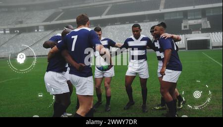 Image of media icons over diverse male rugby team in huddle at stadium. Sport, team, competition, social network, digital interface, internet and comm Stock Photo