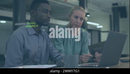 Image of data processing over diverse colleagues using laptop and tablet in office. Business, communication, technology, computing and digital interfa Stock Photo
