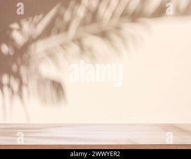 Blurred shadow of tropical palm leaves on beige wall and table top in the foreground. Summer concept. Stock Photo