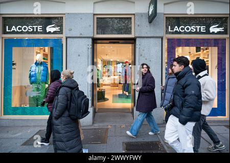 Pedestrians walk past the French clothing brand Lacoste store and logo in Spain Stock Photo Alamy