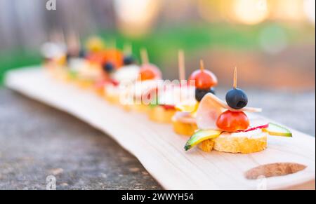 Finger food , various canapes with vegetables, ham, bacon , cheese and olives on wooden table. Stock Photo
