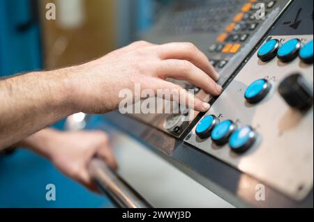 Worker pressing buttons on CNC machine control board in factory. High quality photography. Stock Photo