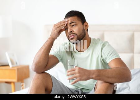 Man on bed with hand on forehead Stock Photo