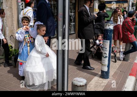 A girl is seen dressed in a white dress as Queen Esther and a boy next to her is dressed as a 'Cohen',  or high priest, according to Jewish Tradition during the Purim celebration. Ultra-Orthodox Jews Celebrate Purim in Bnei Brak, Israel. The holiday commemorates the salvation of the Jews in ancient Persia from a plot to annihilate them. A joyous holiday, it is celebrated by both secular and nonsecular Jews, most notably by dressing up in costumes and drinking, according to the Talmud, “until they cannot distinguish between ‘cursed is Haman’ and ‘blessed is Mordechai.' Stock Photo