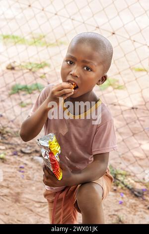 hungry young african child eating snacks, village life in a remote area Stock Photo