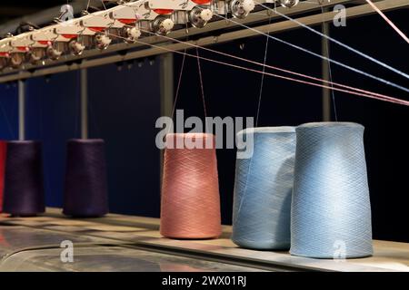 Thread spools and manufacturing equipment. Fabric and textile industry concept. Selective focus. Stock Photo