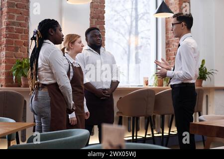 Ethnically diverse young restaurant manager and waiting staff having meeting in morning before opening Stock Photo