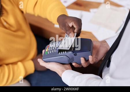 High angle closeup of unrecognizable African American man paying for lunch in restaurant using contactless credit card Stock Photo