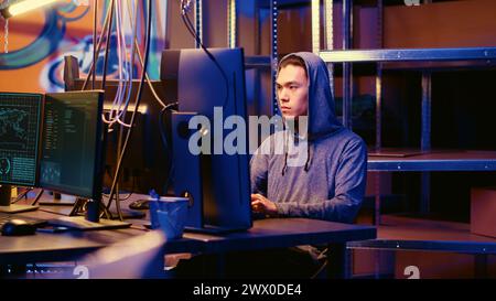 Hacker in graffiti painted underground bunker discussing with colleague about best approach for stealing valuable data using phishing technique, tricking users into revealing sensitive info Stock Photo