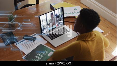 Image of microprocessor connections over african american woman having a image call on laptop. Global networking and business technology concept Stock Photo