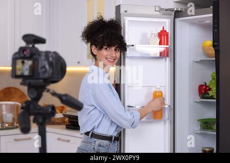 Smiling food blogger explaining something while recording video in kitchen Stock Photo