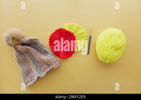 A magenta crocheted cap with woolen yarn and crochet hook displayed on table Stock Photo
