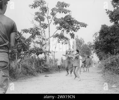 Vietnam War: Members of the 3rd Battalion, 187th Infantry, 101st Airborne Division (Airmobile), join the children of Ap Uu Thoung hamlet in a game of baseball ca. 1970 Stock Photo