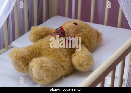 a teddy bear sleeping in a crib, a children's room Stock Photo