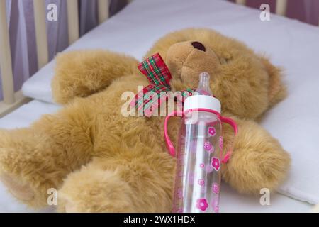 lies in a cradle of a bear with a baby bottle Stock Photo