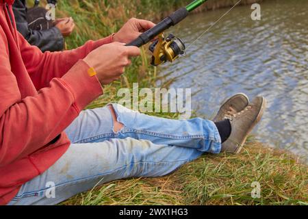 fisherman sitting on the shore of the lake and fishing on a fishing rod Stock Photo
