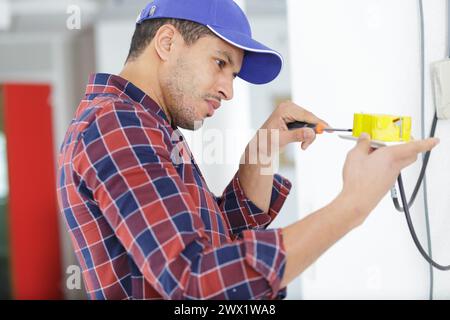 electrician working at plug socket on a wall Stock Photo