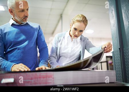 Factory, people and check print quality in creative industry, warehouse and sector for design project. Teamwork, man and woman communication Stock Photo