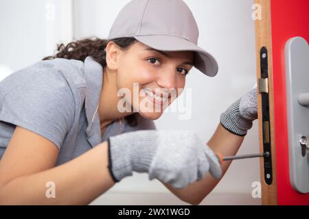 happy female builder using a screwdriver on a door Stock Photo