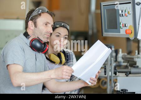 engineer training female apprentice on cnc machine Stock Photo